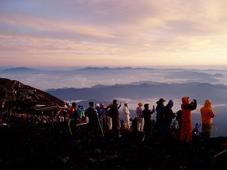 Hundreds of people on the summit of Mount Fuji.  Note how some people are taking pictures of the sunrise with their cell phones.